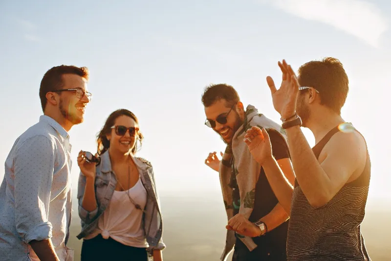 A real photo of four adult friends laughing outdoors