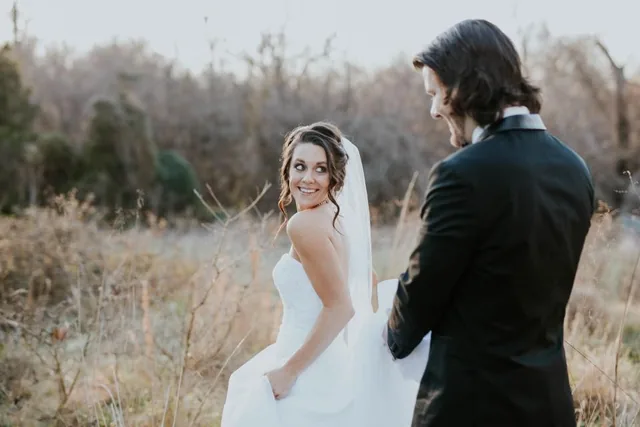 A real wedding photo of a couple in a field, the bride in a white dress